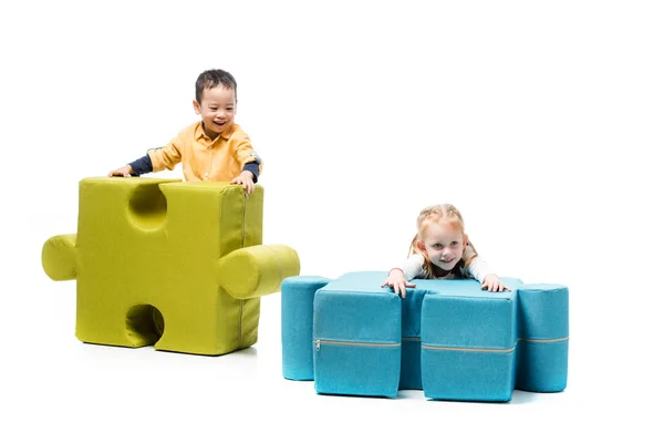 Cheerful multiethnic kids playing with puzzle chairs, on white — Stock Photo