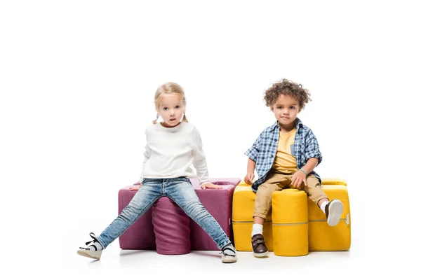 Funny multicultural kids sitting on puzzle chairs, on white — Stock Photo