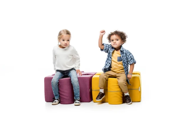 Мультикультурные дети сидят на стульях-головоломках, на белом — стоковое фото