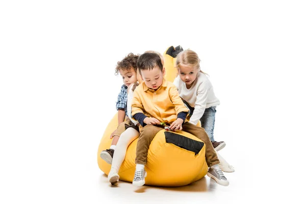 Lustige multikulturelle Kinder sitzen auf einem Müllsackstuhl auf weiß — Stockfoto
