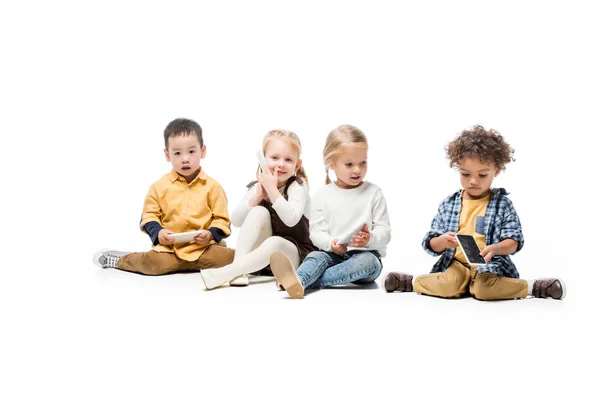 Cheerful multicultural kids using smartphones on white — Stock Photo