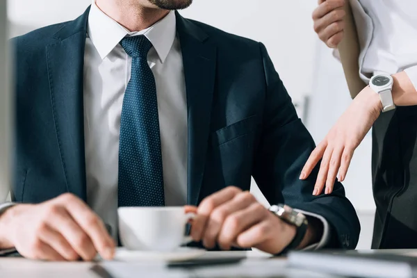 Vue recadrée du secrétaire touchant la main de l'homme d'affaires en fonction — Photo de stock