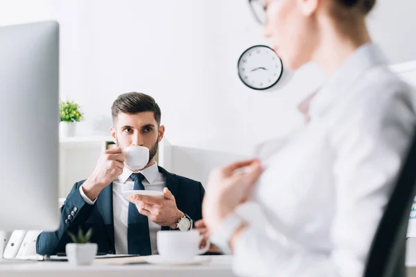 Foco seletivo do empresário beber café e olhar para o secretário no escritório — Fotografia de Stock
