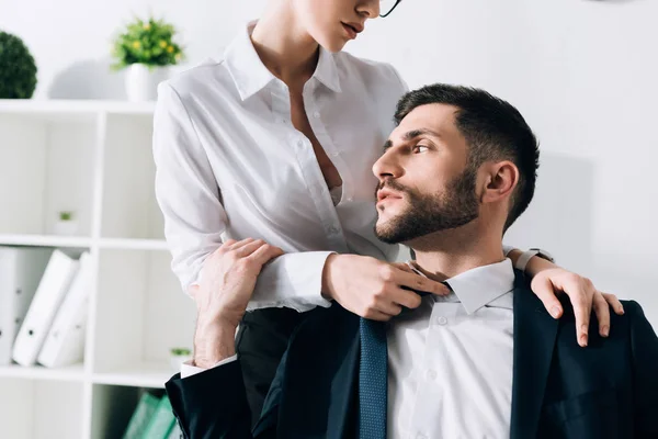 Abgeschnittene Ansicht einer Sekretärin mit großen Brüsten, die einen hübschen Geschäftsmann im Büro umarmt — Stockfoto