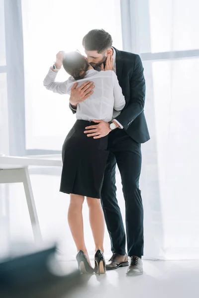 Businessman in suit kissing and hugging secretary in office — Stock Photo