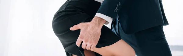 Panoramic shot of businessman in suit hugging secretary in office — Stock Photo