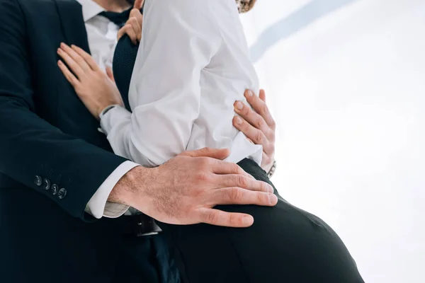 Обрізаний вид бізнесмена в костюмі обіймаючи секретаря в офісі — стокове фото
