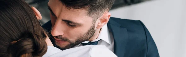 Panoramic shot of businessman hugging and kissing secretary in office — Stock Photo