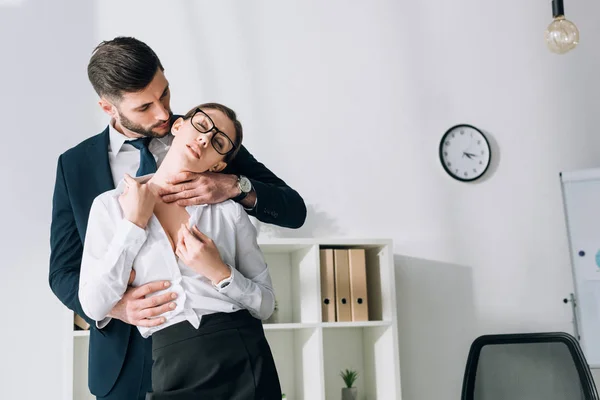 Bel homme d'affaires étreignant secrétaire sexy avec les yeux fermés au bureau — Photo de stock