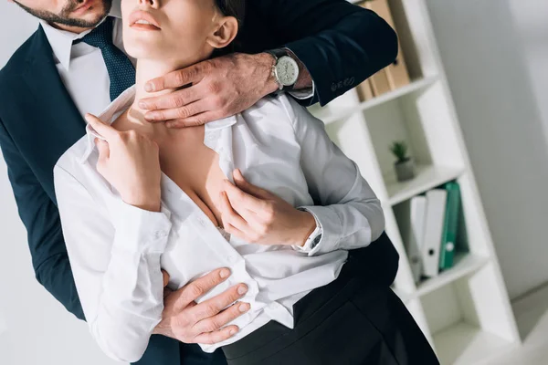 Cropped view of businessman in suit hugging sexy secretary with big breast in office — Stock Photo