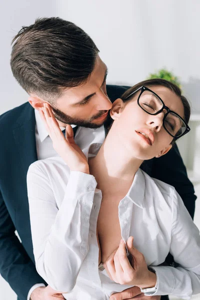 Businessman kissing attractive secretary with big breast in office — Stock Photo