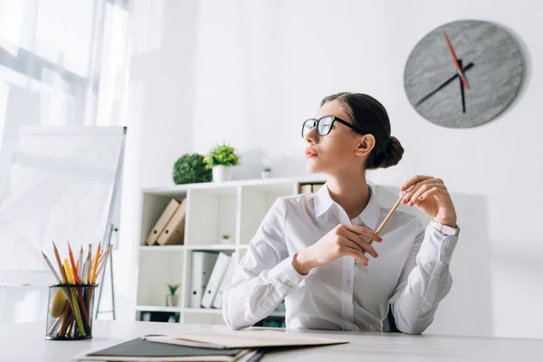 Attraktive Geschäftsfrau sitzt am Tisch und schaut im Büro weg — Stockfoto