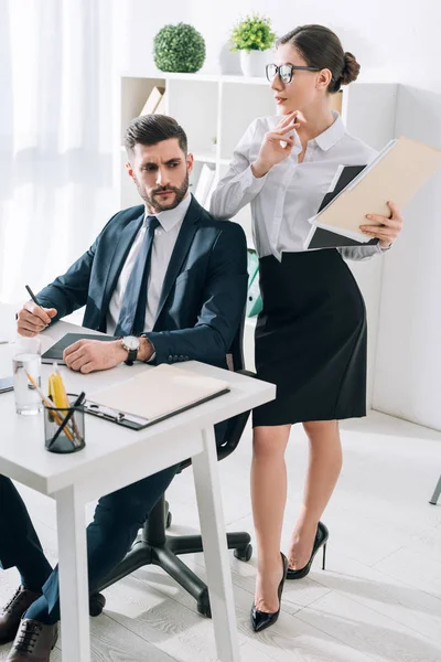 Secrétaire attrayant avec dossier touchant épaule de l'homme d'affaires au bureau — Photo de stock