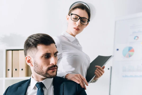 Secrétaire attrayant avec dossier touchant épaule de l'homme d'affaires au bureau — Photo de stock