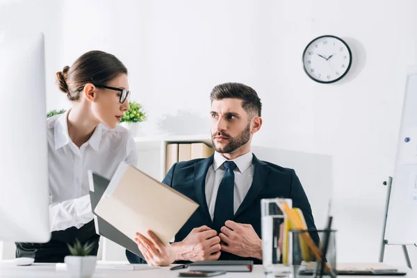 Attraktive Sekretärin zeigt hübschen Geschäftsmann Ordner im Büro — Stockfoto