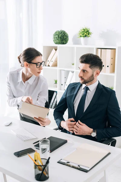 Secrétaire attrayante montrant dossier à beau homme d'affaires au bureau — Photo de stock