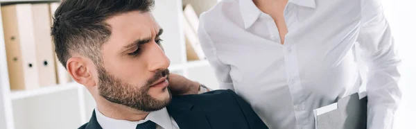 Panoramic shot of secretary with big breast touching shocked businessman in office — Stock Photo