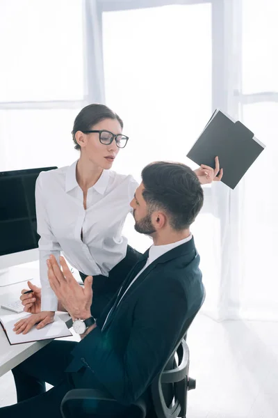 Atractiva secretaria con gran pecho celebración carpeta y seducir a hombre de negocios en la oficina - foto de stock