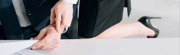 Panoramic shot of secretary touching hand of businessman in office — Stock Photo