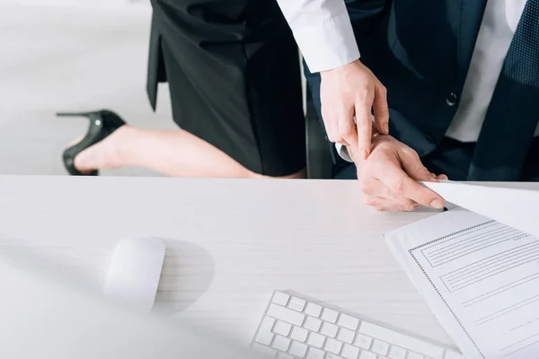 Vue recadrée du secrétaire touchant la main de l'homme d'affaires en fonction — Photo de stock