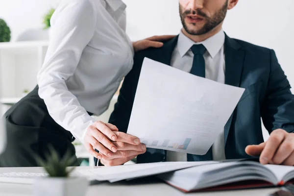 Abgeschnittene Ansicht einer Sekretärin mit großer Brust, die die Hand eines Geschäftsmannes im Büro berührt — Stockfoto