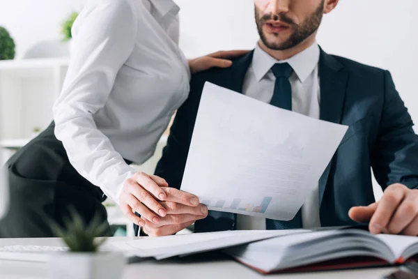 Vue recadrée du secrétaire avec gros sein toucher la main de l'homme d'affaires au bureau — Photo de stock