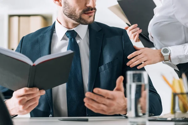 Abgeschnittene Ansicht der Sekretärin, die die Hand eines hübschen Geschäftsmannes im Büro berührt — Stockfoto