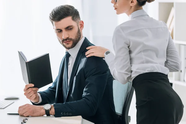 Обрезанный вид секретаря, трогающего плечо привлекательного бизнесмена в офисе — стоковое фото