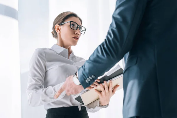Cropped view of businessman touching hand of scared secretary in office — Stock Photo