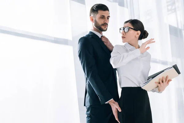 Schöner Geschäftsmann berührt Hintern einer schockierten Sekretärin im Büro — Stockfoto