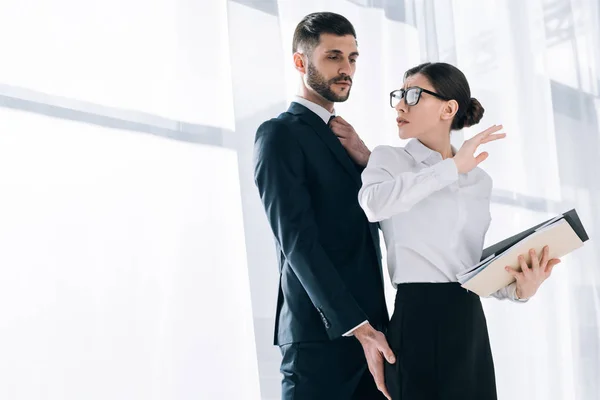 Guapo hombre de negocios tocando el culo de sorprendido secretario en la oficina - foto de stock