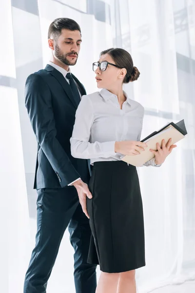 Beau homme d'affaires touchant cul de secrétaire choqué dans le bureau — Photo de stock