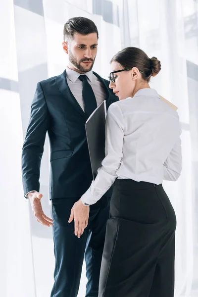 Attractive secretary touching leg of shocked businessman in office — Stock Photo