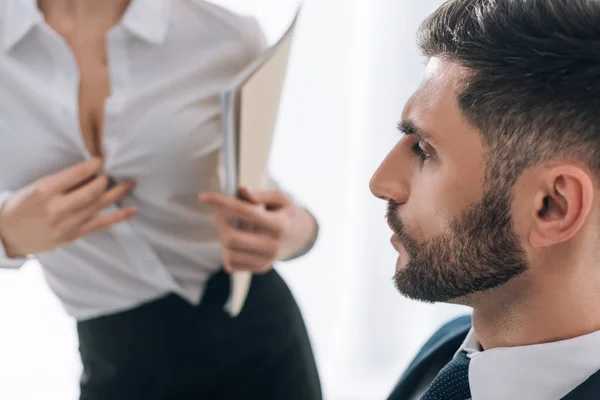 Selective focus of businessman looking at sexy secretary with big breast in office — Stock Photo