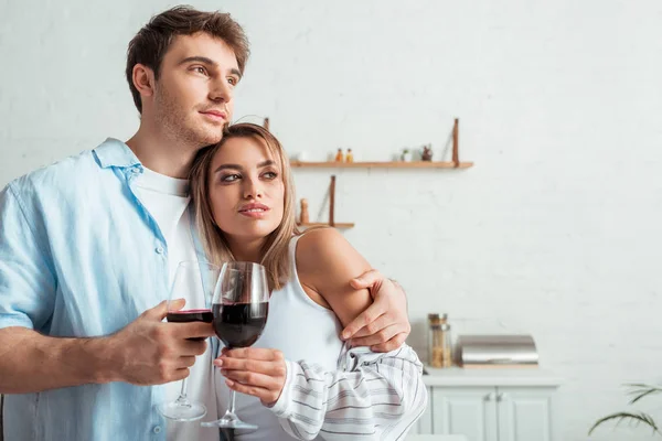 Handsome man and attractive woman holding glasses with red wine — Stock Photo