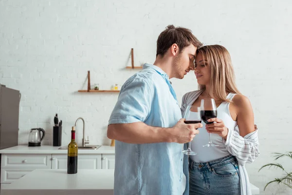 Bell'uomo e donna attraente che tiene bicchieri di vino in cucina — Foto stock
