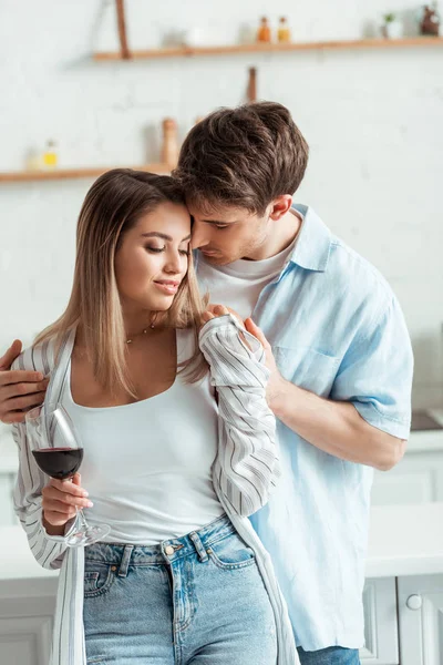 Hombre guapo tocando chica atractiva con copa de vino - foto de stock