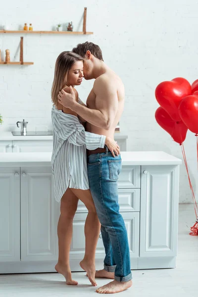 Sem camisa homem em jeans beijando bela mulher na cozinha — Fotografia de Stock