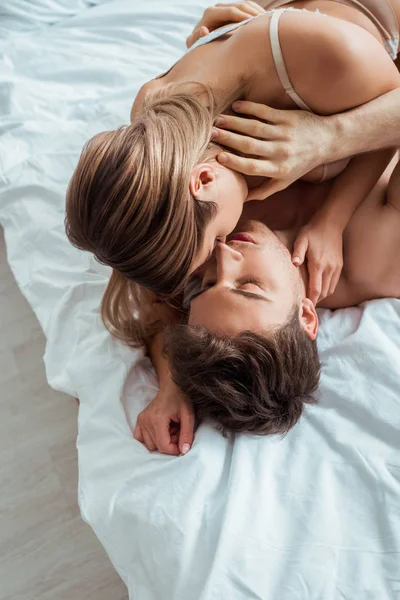 Vista superior del hombre guapo besar a mujer atractiva en el dormitorio - foto de stock