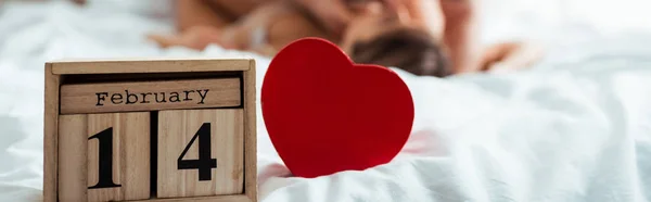 Panoramic shot of wooden cubes with 14 february near sexy couple — Stock Photo