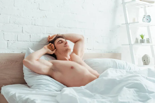 Homem musculoso com os olhos fechados deitado na cama — Fotografia de Stock