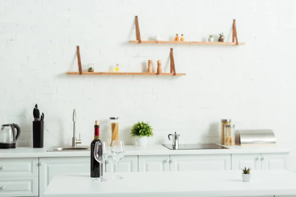 Bottle with red wine near empty glasses on kitchen table — Stock Photo