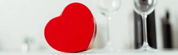 Panoramic shot of red heart-shaped gift box near empty glasses — Stock Photo