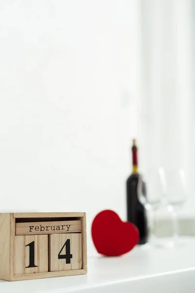 Foco seletivo de cubos de madeira com 14 fevereiro lettering perto de garrafa de vinho e copos — Fotografia de Stock