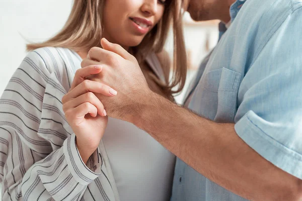 Cropped view of man and happy woman holding hands at home — Stock Photo