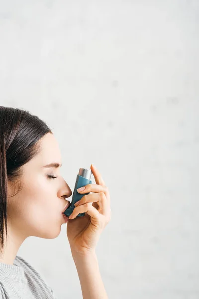 Vue latérale de la femme utilisant un inhalateur sur fond blanc — Photo de stock