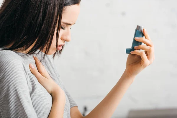 Side view of illness girl holding inhaler at home — Stock Photo