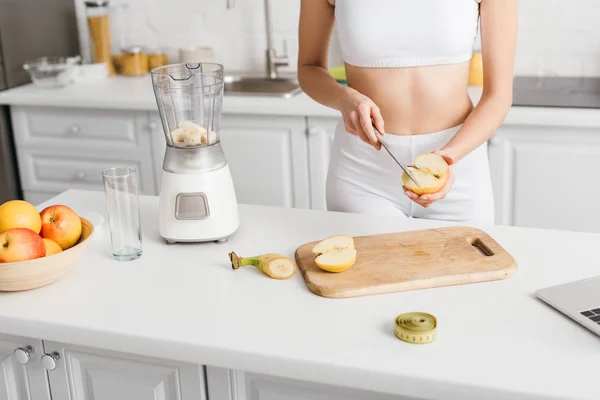 Cropped view of slim sportswoman preparing smoothie near measuring tape on kitchen table — Stock Photo