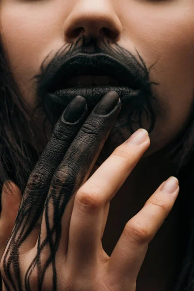 Close up view of woman with black painted hand touching lips — Stock Photo