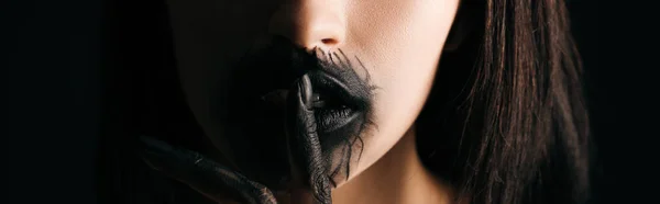 Panoramic shot of woman with black painted lips and hand showing quiet gesture isolated on black — Stock Photo